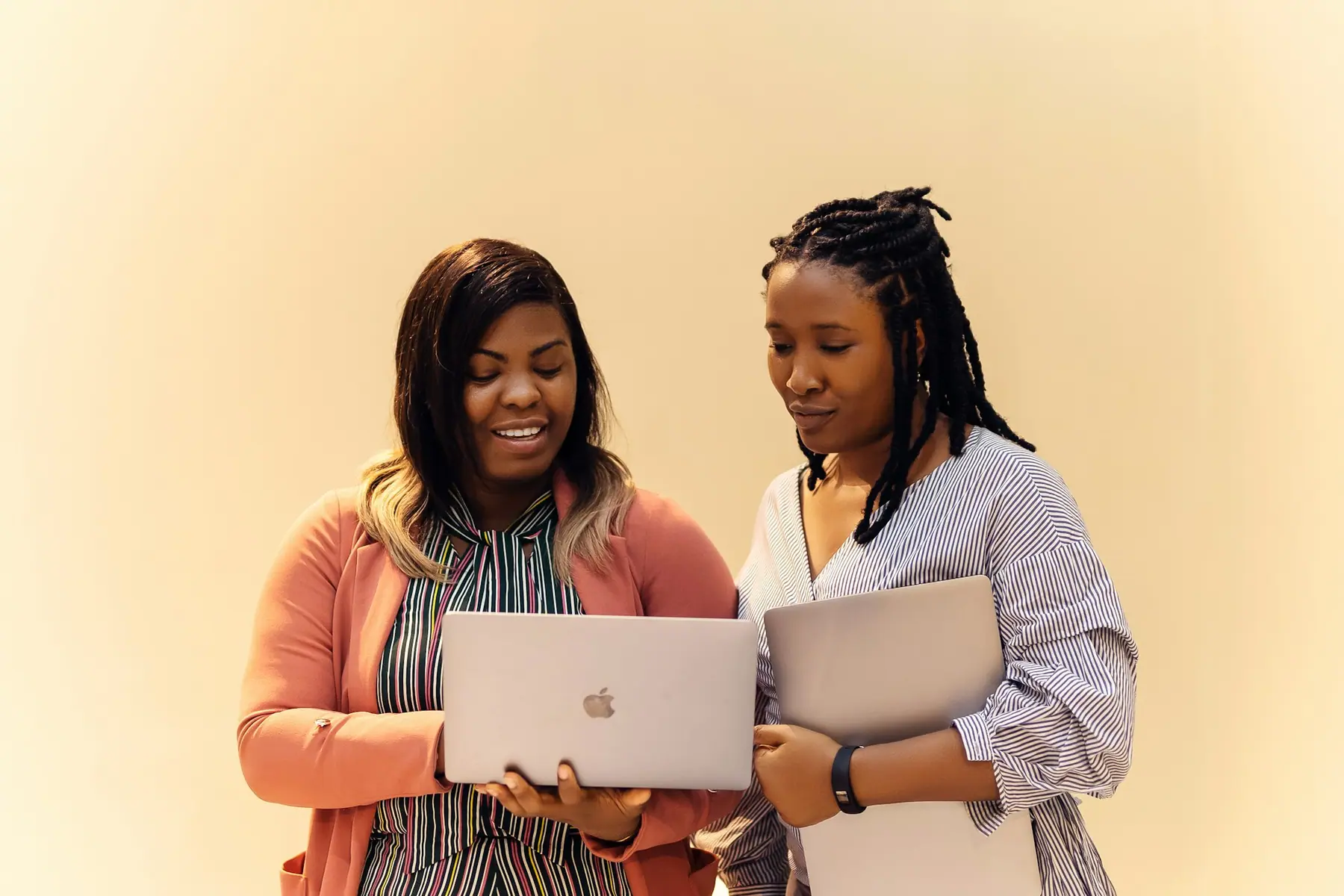 Two colleagues reviewing work together on laptops